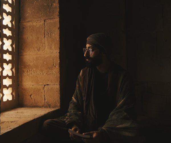 Person meditating peacefully by a window with natural light.